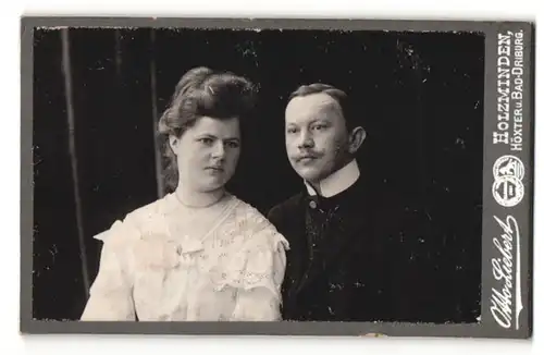 Fotografie Otto Liebert, Holzminden, Frau mit auffällig hoher Frisur mit Mann im Anzug und Schnurrbart.