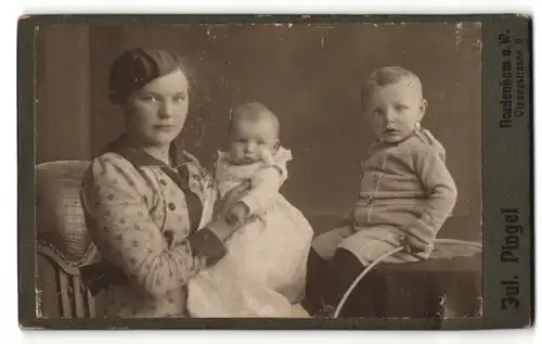 Fotografie Jul. Pingel, Nordenham a. W., Frau im Kleid mit Baby im Arm und Junge auf Tisch sitzend