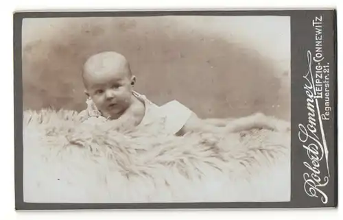 Fotografie Robert Sommer, Leipzig-Connewitz, Portrait niedliches Baby im weissen Hemd auf Fell liegend