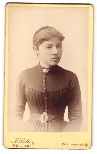 Fotografie J. Seiling, München, Portrait junge Dame mit zurückgebundenem Haar und Kragenbrosche