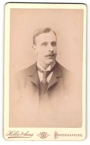 Fotografie Hellis & Sons, London, Portrait Herr mit Oberlippenbart in Anzug mit Garderobe