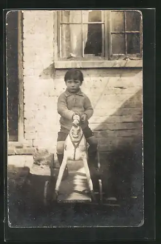 Foto-AK Kleiner Junge auf einem Spielzeugpferd