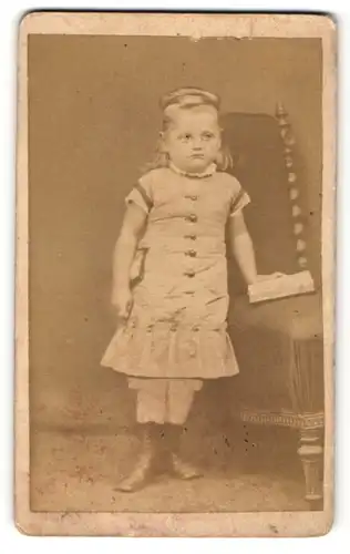 Fotografie Ch. Brandes, Hildesheim, Portrait modisch gekleidetes Mädchen mit Buch an Stuhl gelehnt