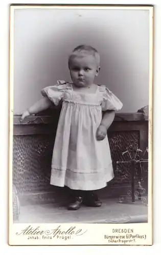 Fotografie Atelier Apollo, Dresden, Portrait Kleinkind mit kurzem Haar in weissem Kleid