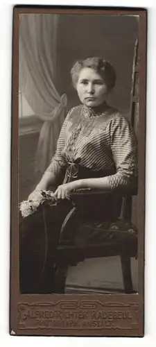 Fotografie Alfred Richter, Radebeul, Portrait sitzende Dame in gestreifter Bluse mit Blume