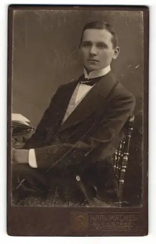 Fotografie Karl Mäckel, Burgstädt, Portrait junger Mann im Anzug auf einem Stuhl