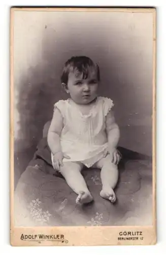 Fotografie Adolf Winkler, Görlitz, Portrait Kleinkind im Kleidchen auf einem Kissen