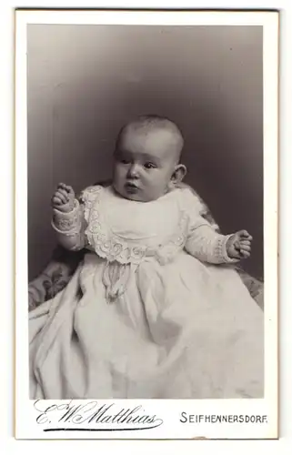 Fotografie E. W. Matthias, Seifhennersdorf, Baby im Kleidchen sitzend