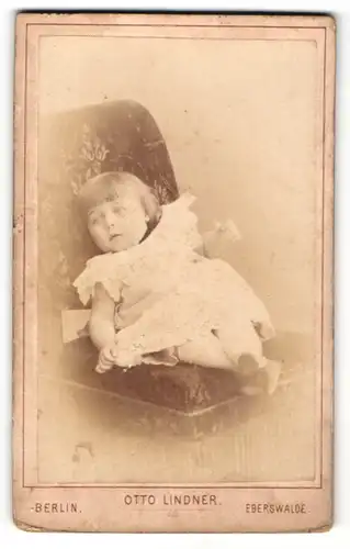Fotografie Otto Lindner, Berlin, kleines Mädchen auf Sessel liegend