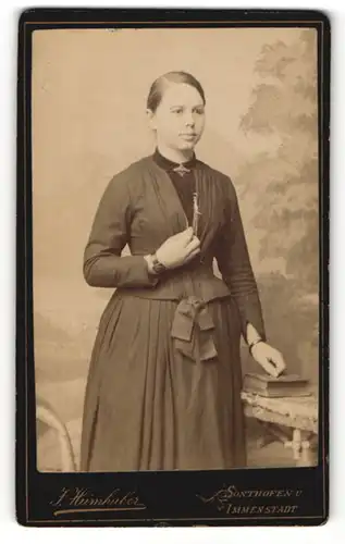 Fotografie J. Heimhuber, Sonthofen, Portrait bürgerlich gekleidete Dame mit Buch an Tisch gelehnt