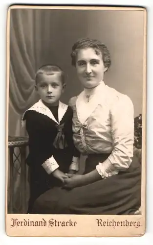 Fotografie Ferdinand Stracke, Reichenberg, Portrait lächelnde Mutter mit niedlichem Buben im Matrosenanzug