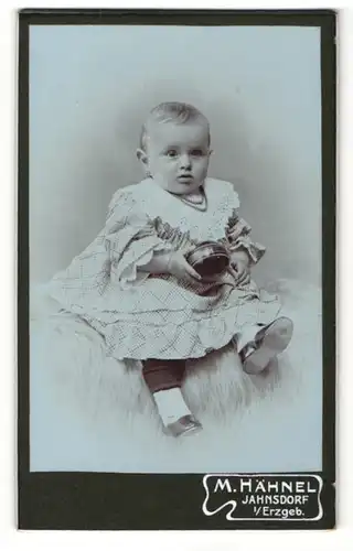 Fotografie M. Hähnel, Jahnsdorf / Erz., Portrait Kleinkind im weissen Kleid mit Dose in der Hand