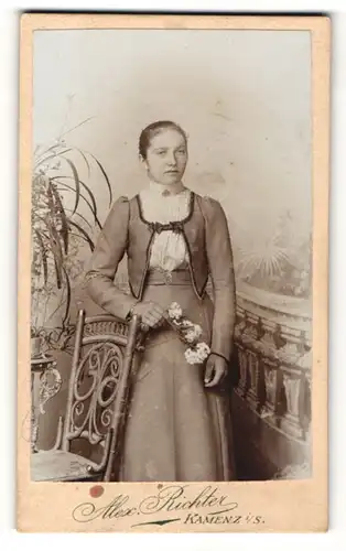 Fotografie Alex. Richter, Kamenz i. S., Frau im Kleid mit Blumenzweig stehend