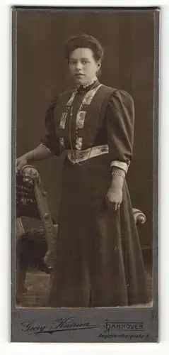 Fotografie Georg Knirim, Hannover, Portrait hübsch gekleidete Dame an Stuhl gelehnt