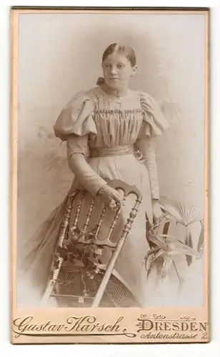 Fotografie Gustav Karsch, Dresden, Portrait hübsch gekleidete Dame mit Blume an Stuhl gelehnt