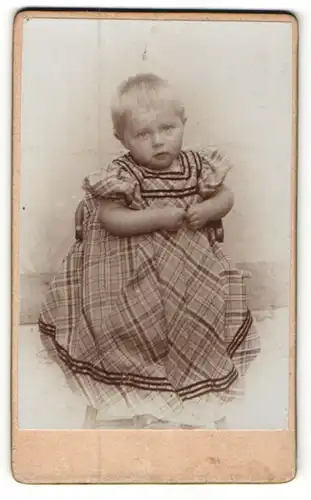 Fotografie unbekannter Fotograf und Ort, Kleinkind in kariertem Kleidchen