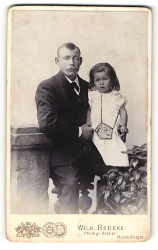 Fotografie Wilh. Redeke, Hildesheim, Vater mit Schnurrbart im Anzug mit seiner Tochter im Arm