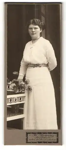 Fotografie H. Behning, Buxtehude, Portrait dunkelhaarige Schönheit mit Blumen im weissen Kleid