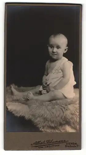 Fotografie Albert Schumann, Stendal, Portrait bezaubernder kleiner Bube im Hemdchen auf Fell sitzend