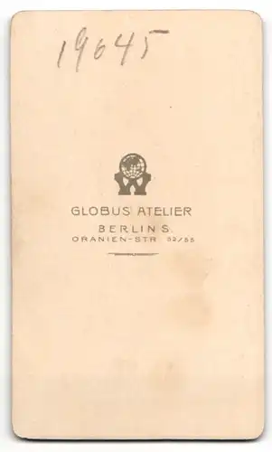 Fotografie Atelier Globus, Berlin, Portrait Knabe im schwarzen Anzug neben einem Stuhl
