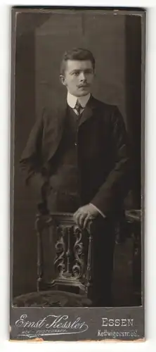 Fotografie Ernst Kessler, Essen, Portrait elegant gekleideter Herr mit Schnurrbart an Stuhl gelehnt