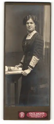 Fotografie Fritz Hacker, Annaberg i / S., Portrait hübsch gekleidete Dame mit Zeitung an Tisch gelehnt