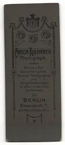 Fotografie Anton Kulhanek, Berlin, Portrait charmanter Herr im Anzug mit Fliege an Tisch gelehnt