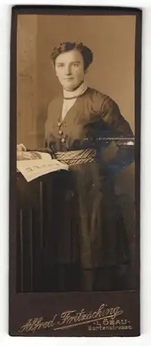 Fotografie Alfred Fritzsching, Löbau, Portrait modisch gekleidete Dame mit Zeitung an Tisch gelehnt