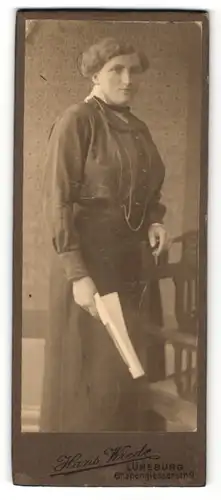Fotografie Hans Wrede, Lüneburg, Portrait bürgerlich gekleidete Dame mit Zeitung an Stuhl gelehnt