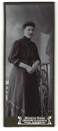 Fotografie Wilhelm Riege, Lüneburg, Portrait elegant gekleidete Dame an Tisch gelehnt