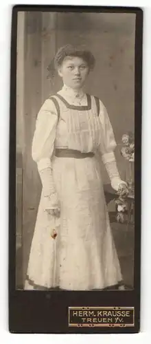 Fotografie Herm. Krause, Treuen i. V., Junge Dame mit Hochsteckfrisur in plissiertem Trägerkleid mit Handschuhe