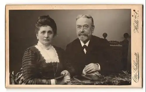 Fotografie Otto Gebhardt, Halle a / S., Portrait bürgerliche gekleidetes Paar mit Büchlein am Tisch sitzend