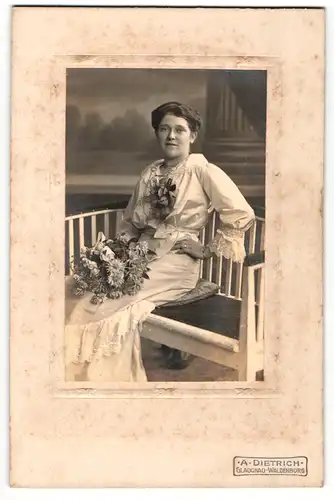 Fotografie A. Dietrich, Glauchau, Portrait sitzende Dame im weissen Kleid mit Ansteckblumen und Blumenstauss