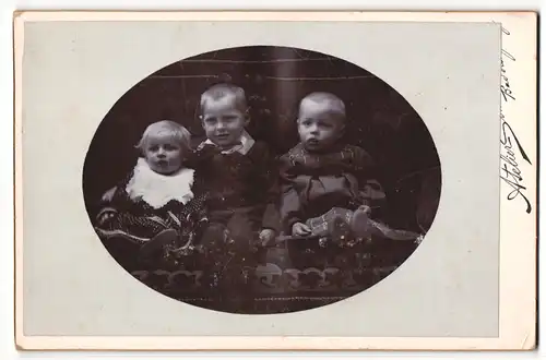 Fotografie unbekannter Fotograf und Ort, Portrait drei Kleinkinder auf Sitzmöbel