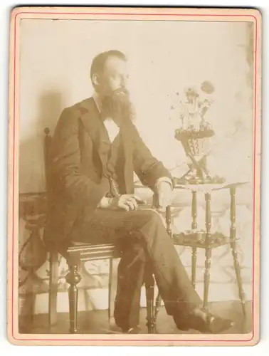 Fotografie unbekannter Fotograf und Ort, Portrait elegant gekleideter Herr mit Vollbart am Tisch sitzend