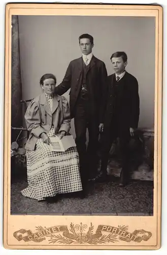 Fotografie Cabinet Portrait, unbekannter Ort, Portrait sitzende Dame und zwei junge Männer in hübscher Kleidung