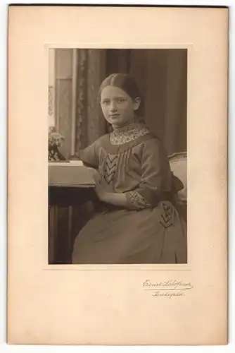 Fotografie Ernst Lohöfener, Bielefeld, Portrait modisch gekleidetes Mädchen mit Buch am Tisch sitzend