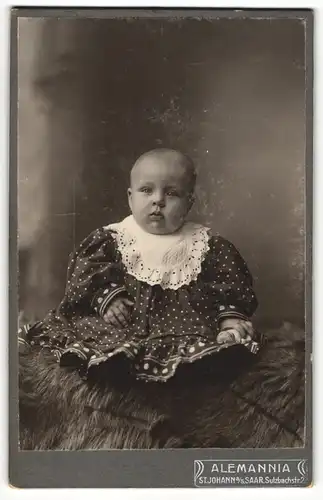 Fotografie Atelier Alemannia, St. Johann / Saar, Baby trägt Kleidchen und Latz