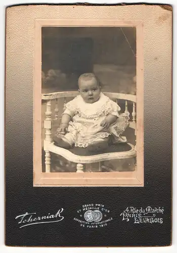 Fotografie Tcherniak, Paris, Portrait sitzendes Baby im hübschen Kleid mit Armband