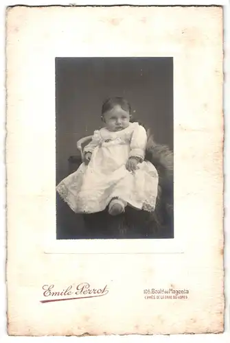 Fotografie Emile Perrot, Paris, Portrait sitzendes Kleinkind im hübschen Kleid mit Brosche