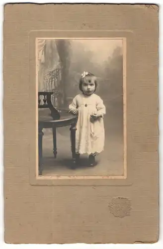 Fotografie Sarrazin, Poissy, Portrait hübsch gekleidetes kleines Mädchen an Stuhl gelehnt