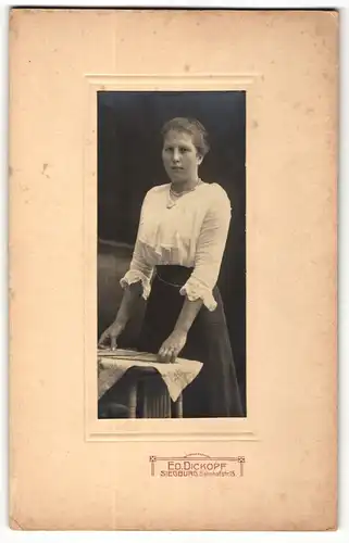 Fotografie Ed. Dickopf, Siegburg, Portrait modisch gekleidete Dame mit Karten an Tisch gelehnt