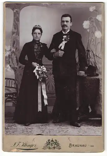 Fotografie J. F. Klinger, Braunau a / Inn, Portrait bürgerliches Paar in Hochzeitskleidung mit Blumenstrauss