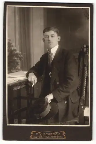 Fotografie F. X. Schröck, Laufen a / d. Salzach, Portrait elegant gekleideter Herr mit Zigarette am Tisch sitzend