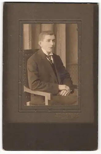 Fotografie Rud. Rosenkranz, Mügeln, Portrait sitzender junger Mann im Anzug mit Krawatte