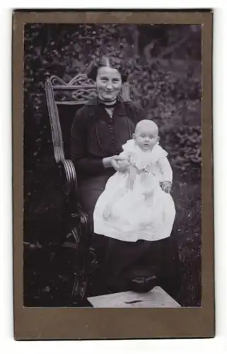 Fotografie Fotograf & Ort unbekannt, Portrait Mutter mit Baby im Gartenstuhl sitzend