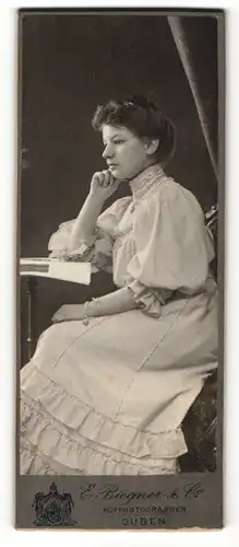 Fotografie E. Biegner & Co., Guben, Portrait hübsch gekleidete Dame mit Zeitung am Tisch sitzend