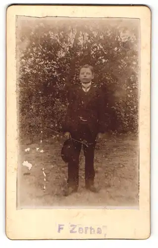 Fotografie F. Zerbe, unbekannter Ort, Portrait kleiner Junge im Anzug mit Stock und Hut