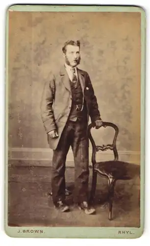 Fotografie J. Brown, Rhyl, Portrait stattlicher junger Mann mit Koteletten im Anzug