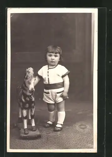 AK Kleinkind steht neben einem Schaukelpferd